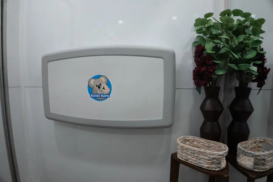 Fold-down Koala Kare baby changing station beside dark vases and woven baskets