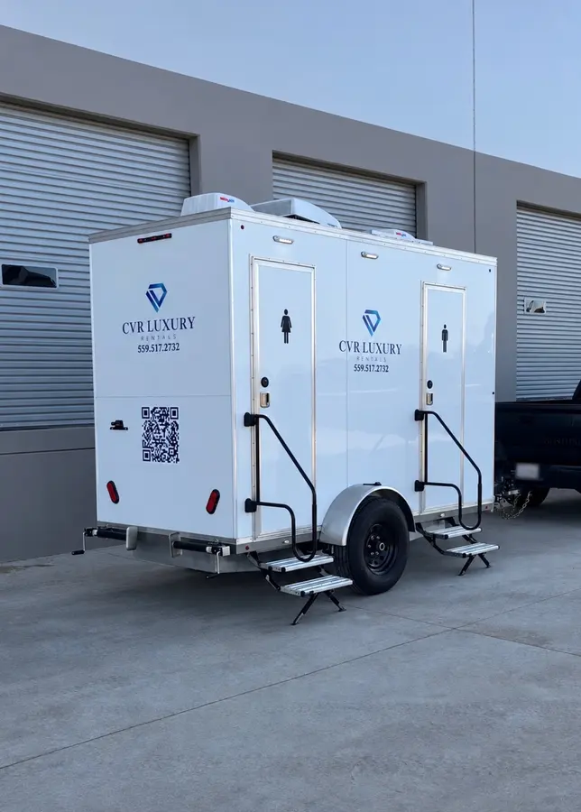 The CVR Luxury Rentals trailer from the rear corner, showing both entries with fold-out steps and handrails