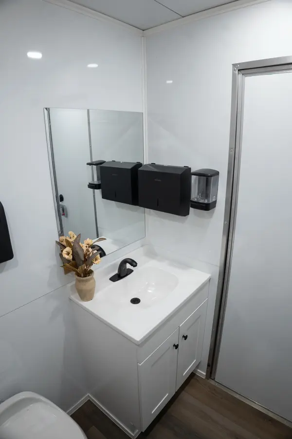 Vanity with a black faucet, mirror, and mounted soap and paper towel dispensers